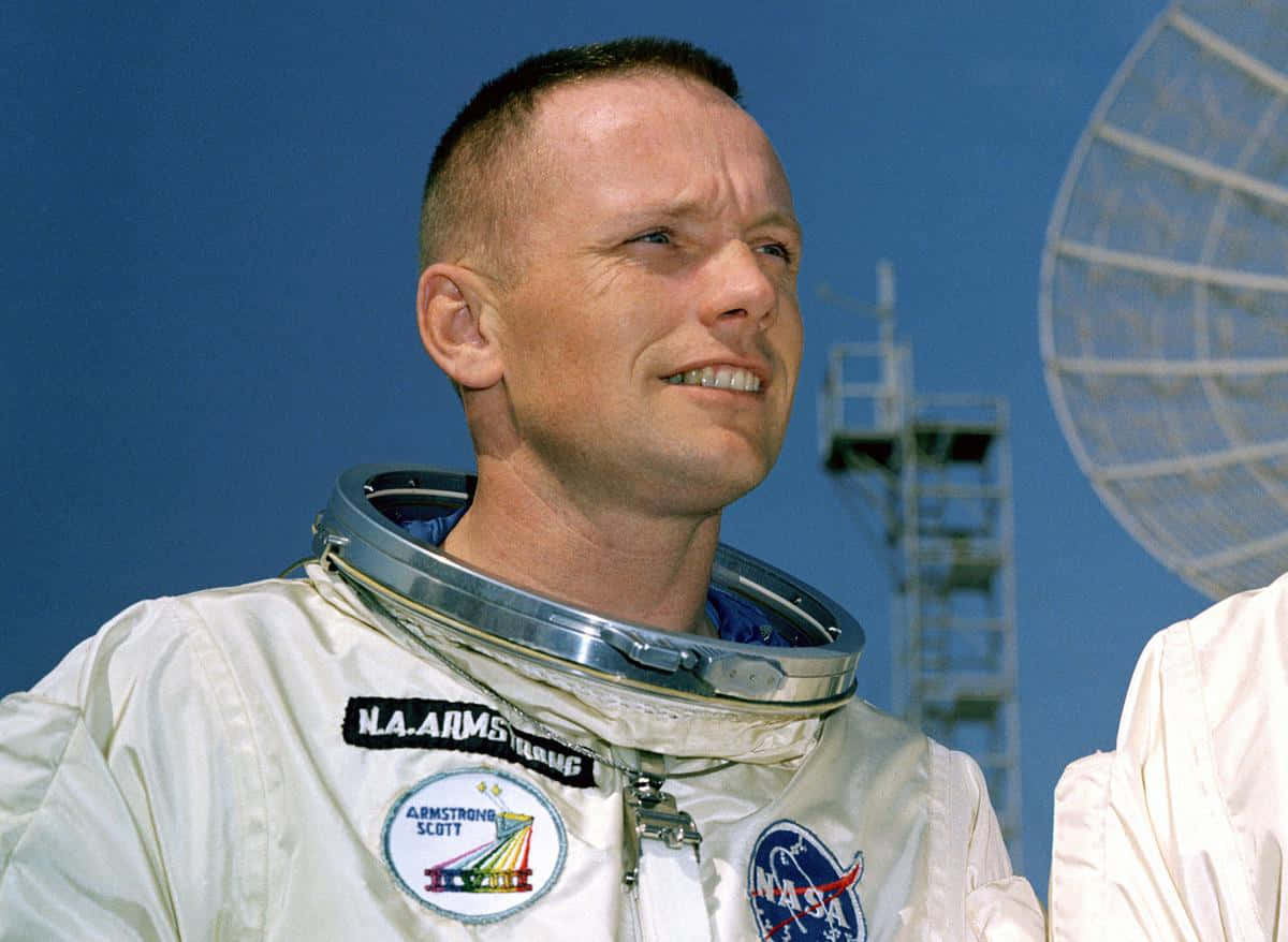 Neil Armstrong 桌布 壁紙 — 太空人尼爾·阿姆斯壯身穿白色NASA太空衣，在晴朗藍天下微笑，背景有衛星天線。