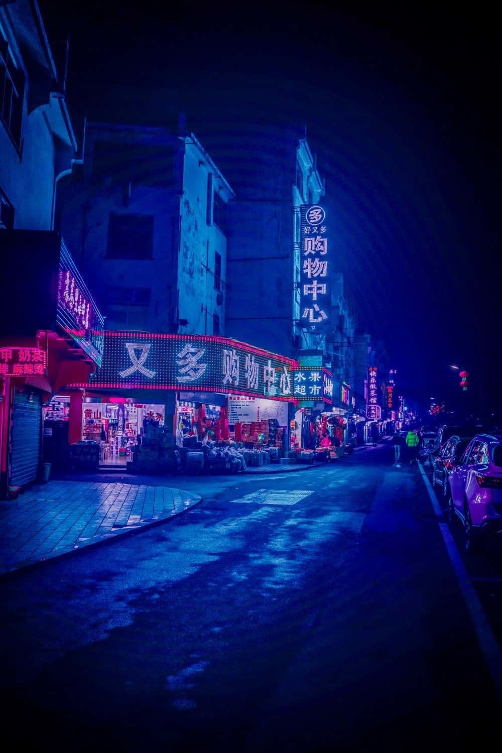  壁紙 — 夜晚一條霓虹燈照亮的城市小巷，發光招牌在黑暗天空下的濕漉漉路面反射。