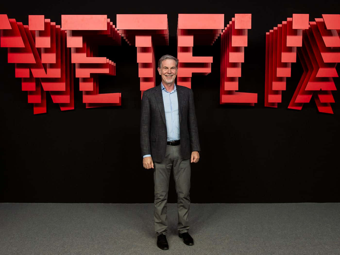 Netflix 的 John Savage 站在 Netflix 標誌前擺姿勢 壁紙