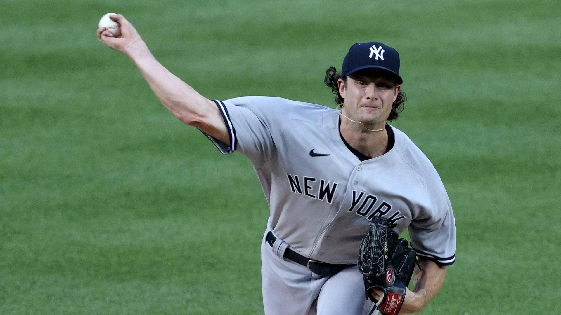 紐約洋基隊投手在夜間綠色球場上投擲棒球。 — MLB 壁紙
