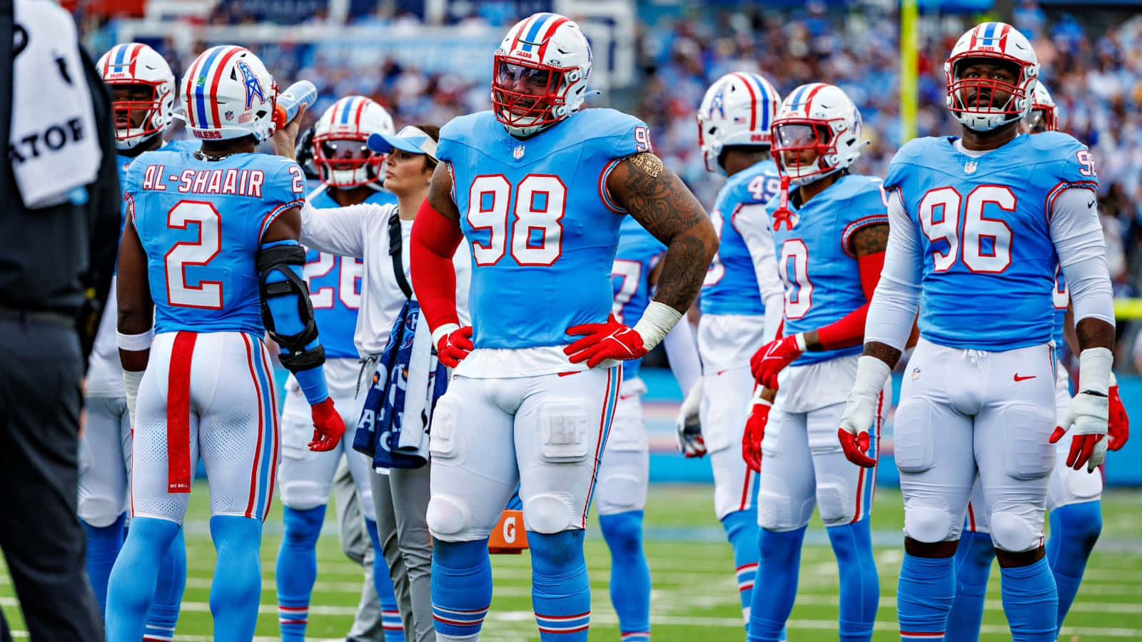  壁紙 — NFL防守線鋒穿著藍白球衣，在比賽中專注地站在綠色球場上。