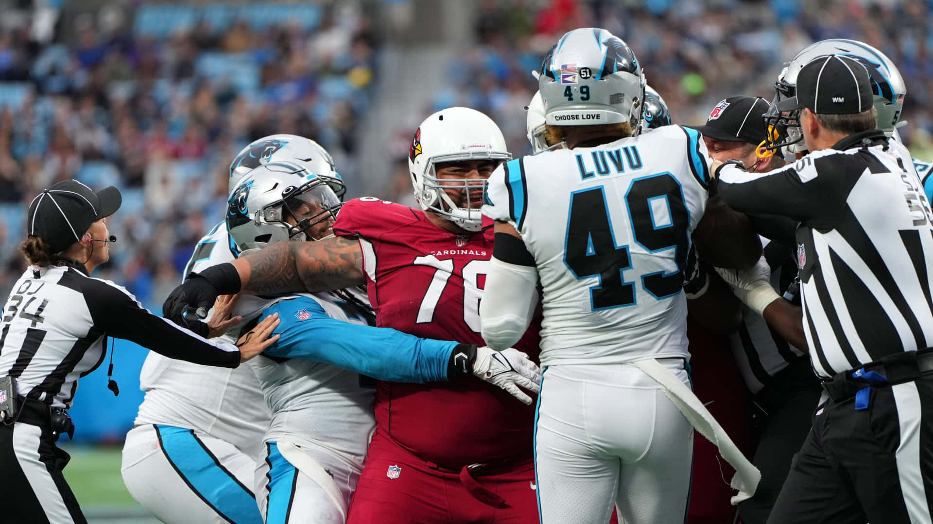  壁紙 — 身穿紅白球衣的NFL球員在美式足球比賽中激烈碰撞，裁判介入調停。