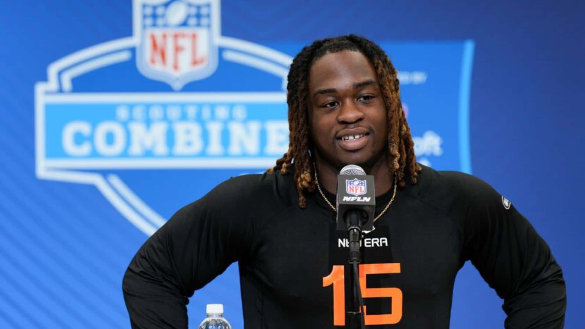  壁紙 — NFL 球員身穿黑色球衣，橙色15號，在Scouting Combine記者會上對著麥克風發言。