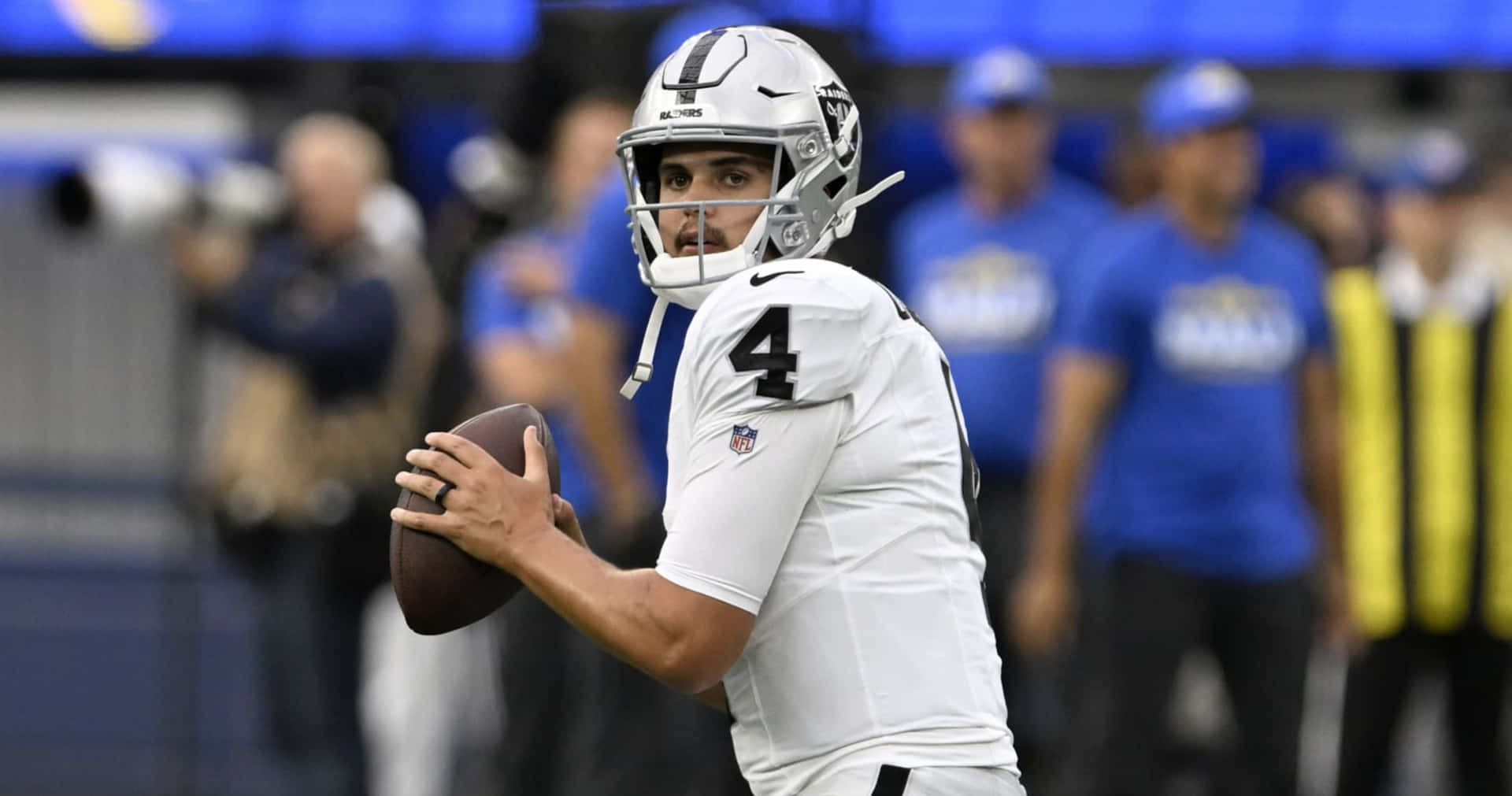  壁紙 — 一位專注的NFL四分衛身穿白色球衣和銀色頭盔，準備在比賽中擲出橄欖球。
