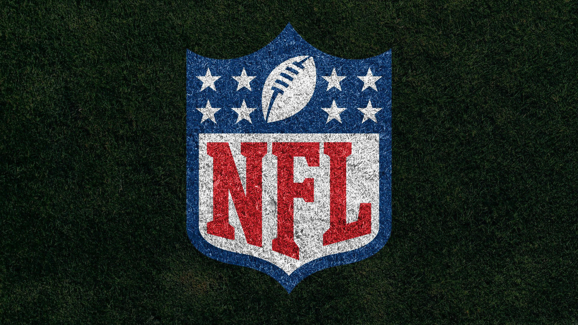 NFL Teams 桌布 壁紙 — NFL 標誌，紅、白、藍盾牌，帶星星和橄欖球，背景為有紋理的綠色草地。