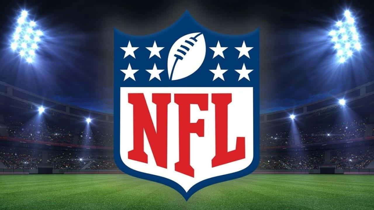 NFL 桌布 壁紙 — NFL 標誌位於充滿活力的綠色足球場中央，在明亮的體育場燈光下，背景有歡呼的人群。