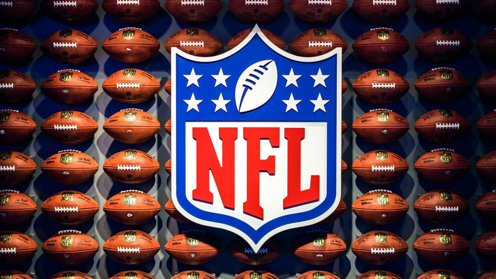 NFL 桌布 壁紙 — NFL 標誌置中於棕色美式足球牆上，在明亮的攝影棚燈光下。