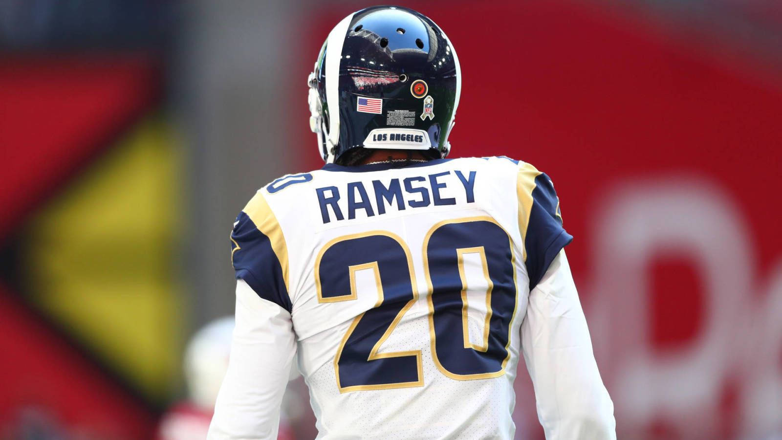 足球 桌布 壁紙 — NFL 球員 Ramsey 身穿白色和金色 20 號球衣，戴著頭盔，背對鏡頭，背景是模糊的體育場。