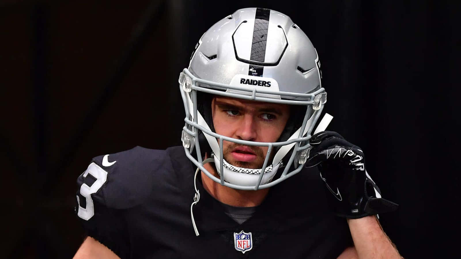 突襲者 桌布 壁紙 — NFL 美式足球員戴上 Raiders 頭盔和球衣，近距離凝視鏡頭。