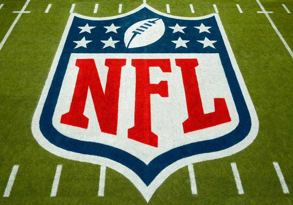 Football Field 桌布 壁紙 — NFL標誌的特寫，以鮮明的紅、白、藍色繪製在充滿活力的綠色足球場草地上，並帶有白色碼線。
