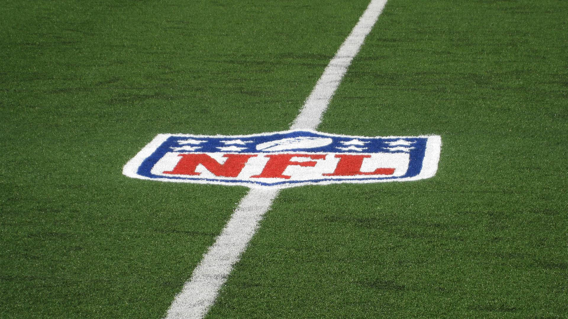 NFL 美式足球 桌布 壁紙 — NFL標誌的特寫，塗在充滿活力的綠色草地上，有一條清晰的白色碼線穿過。