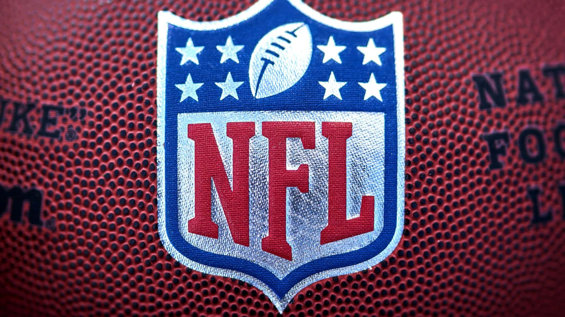 NFL 桌布 壁紙 — NFL標誌的特寫，繡在帶有紋理的棕色皮革橄欖球上，可見縫線和品牌文字。