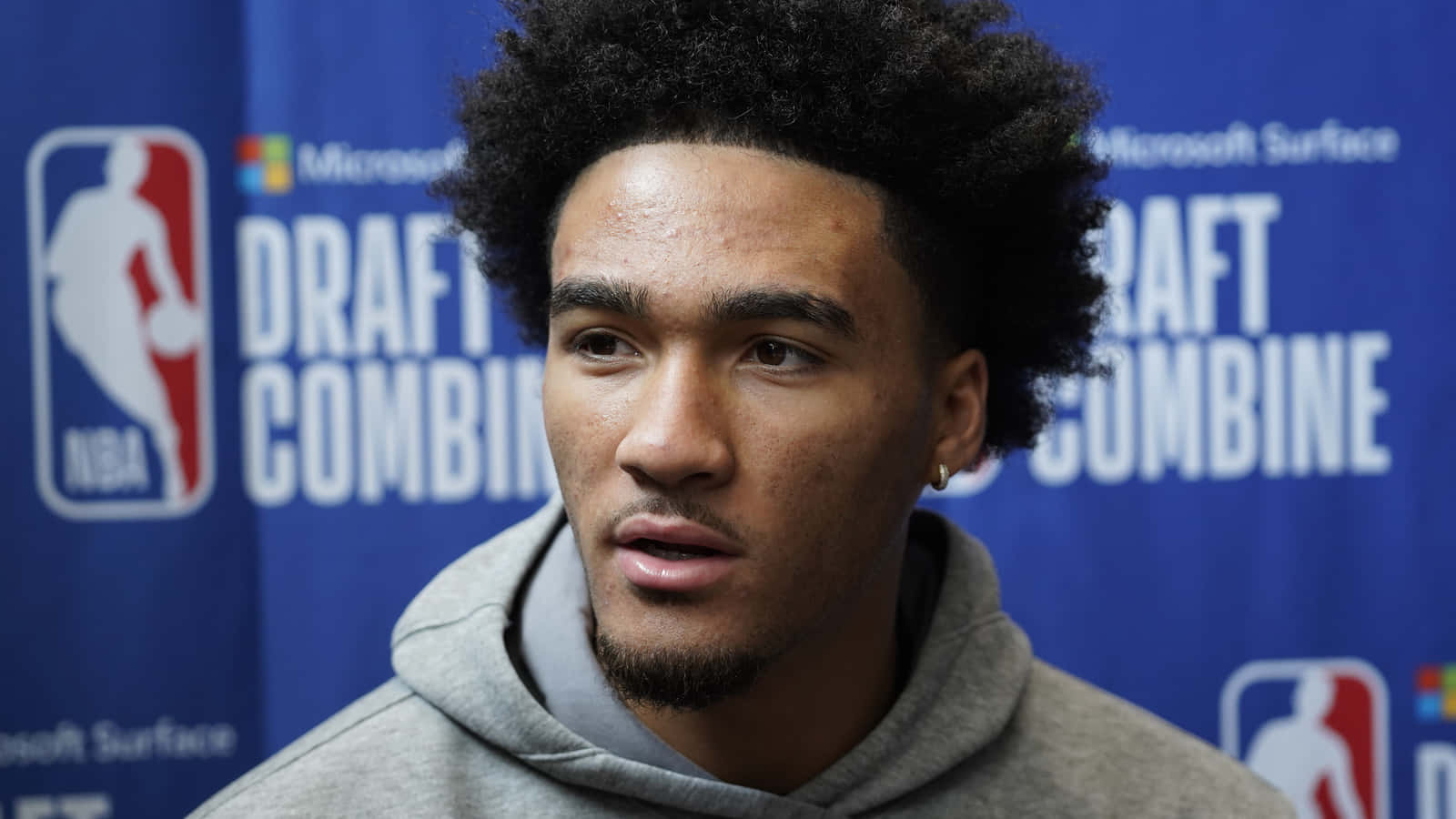  壁紙 — 年輕籃球運動員，留著非洲式髮型，身穿灰色連帽衫，在NBA選秀聯合試訓記者會上發言。