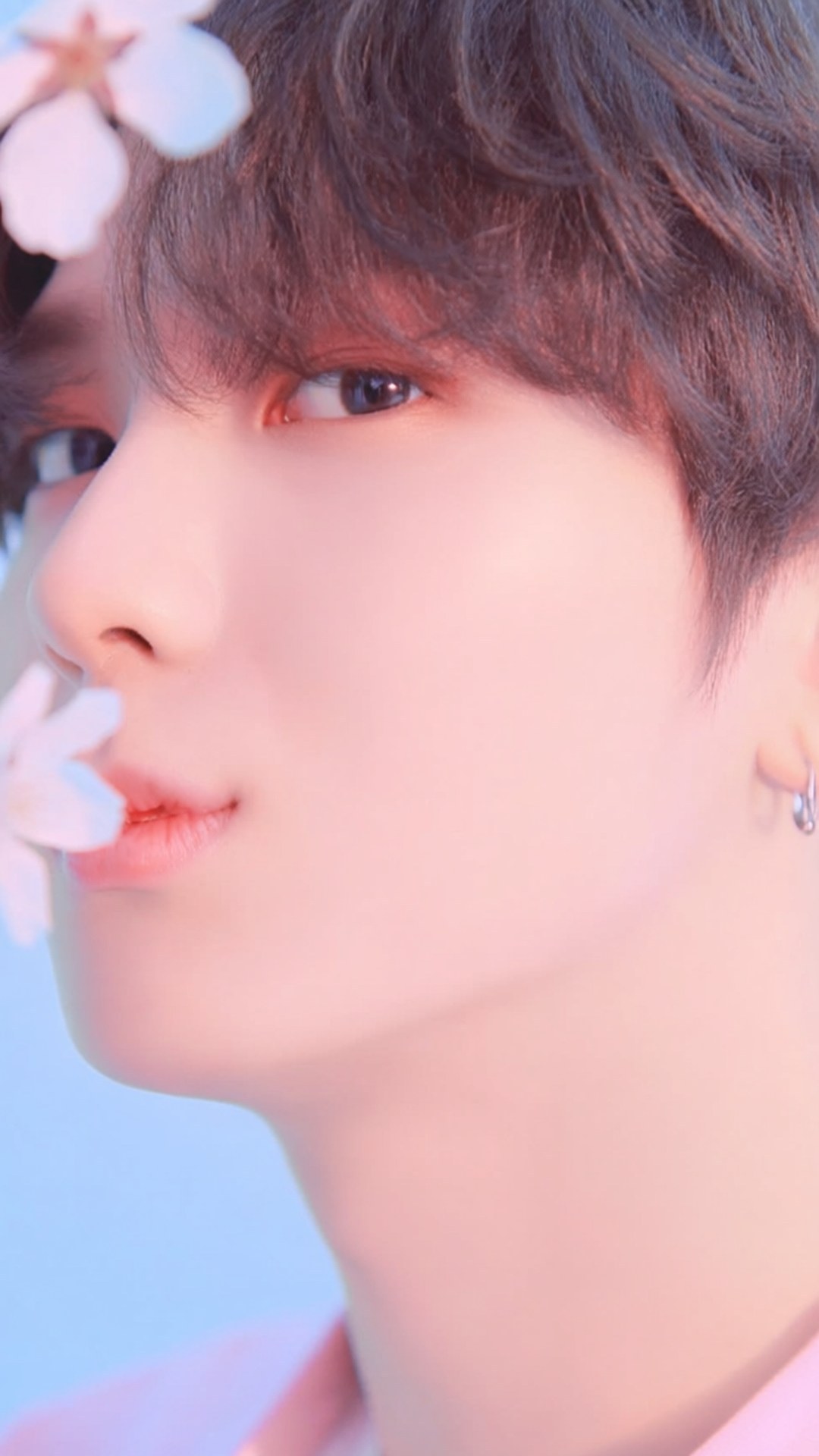 Dreamy Jaehyun 壁紙 — 一位黑髮年輕男子在柔和粉紅燈光下，櫻花飄近他的臉龐，他溫柔地凝視著。