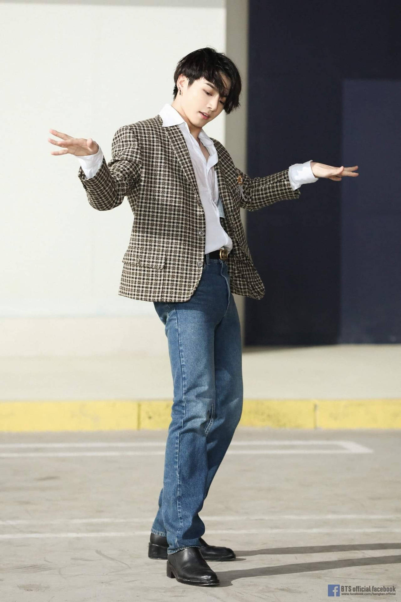 年輕男子身穿格紋西裝外套和牛仔褲在停車場擺姿勢 — Jungkook 壁紙