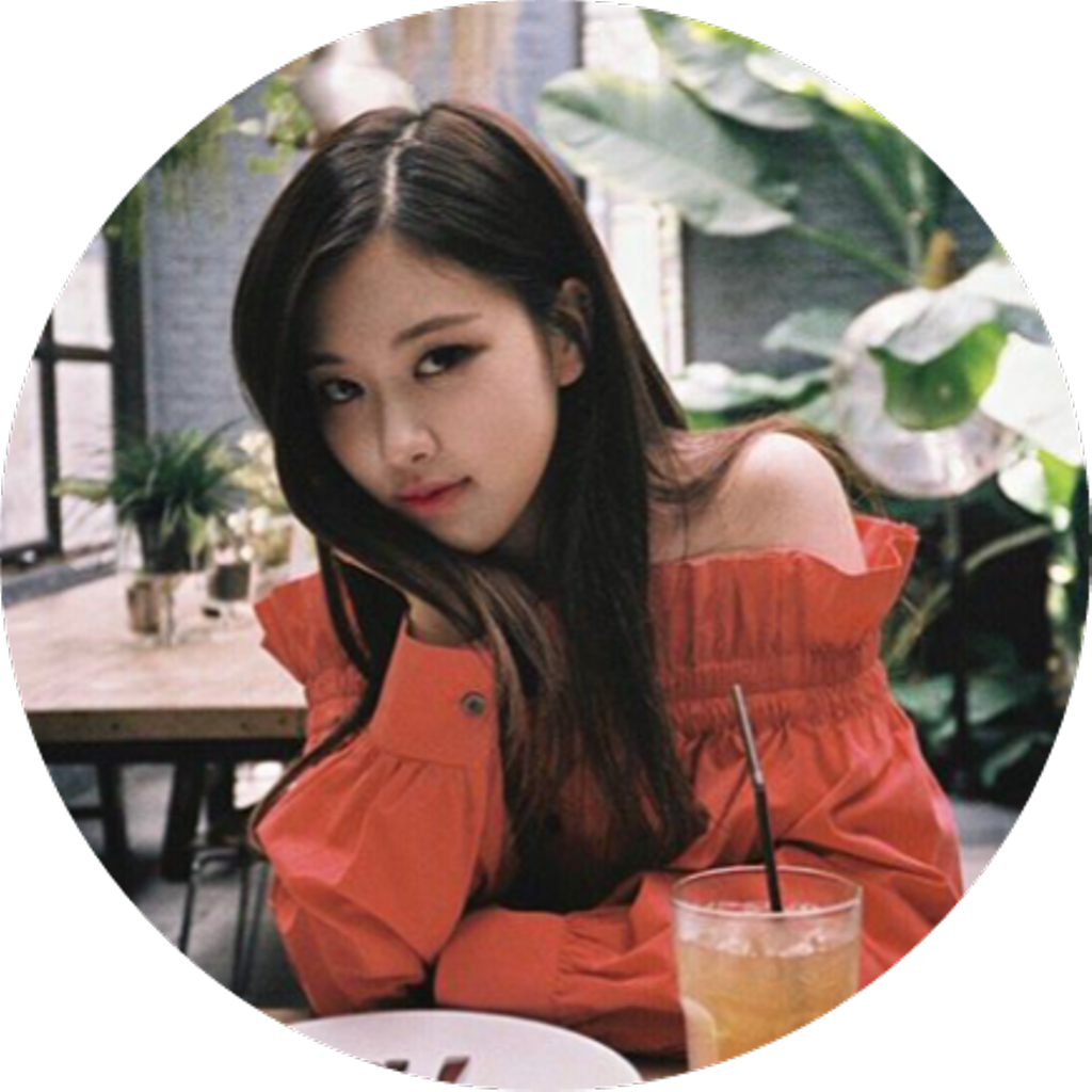 身穿橙色上衣的年輕女性坐在咖啡廳，周圍有飲品和植物。 — Blackpink 壁紙