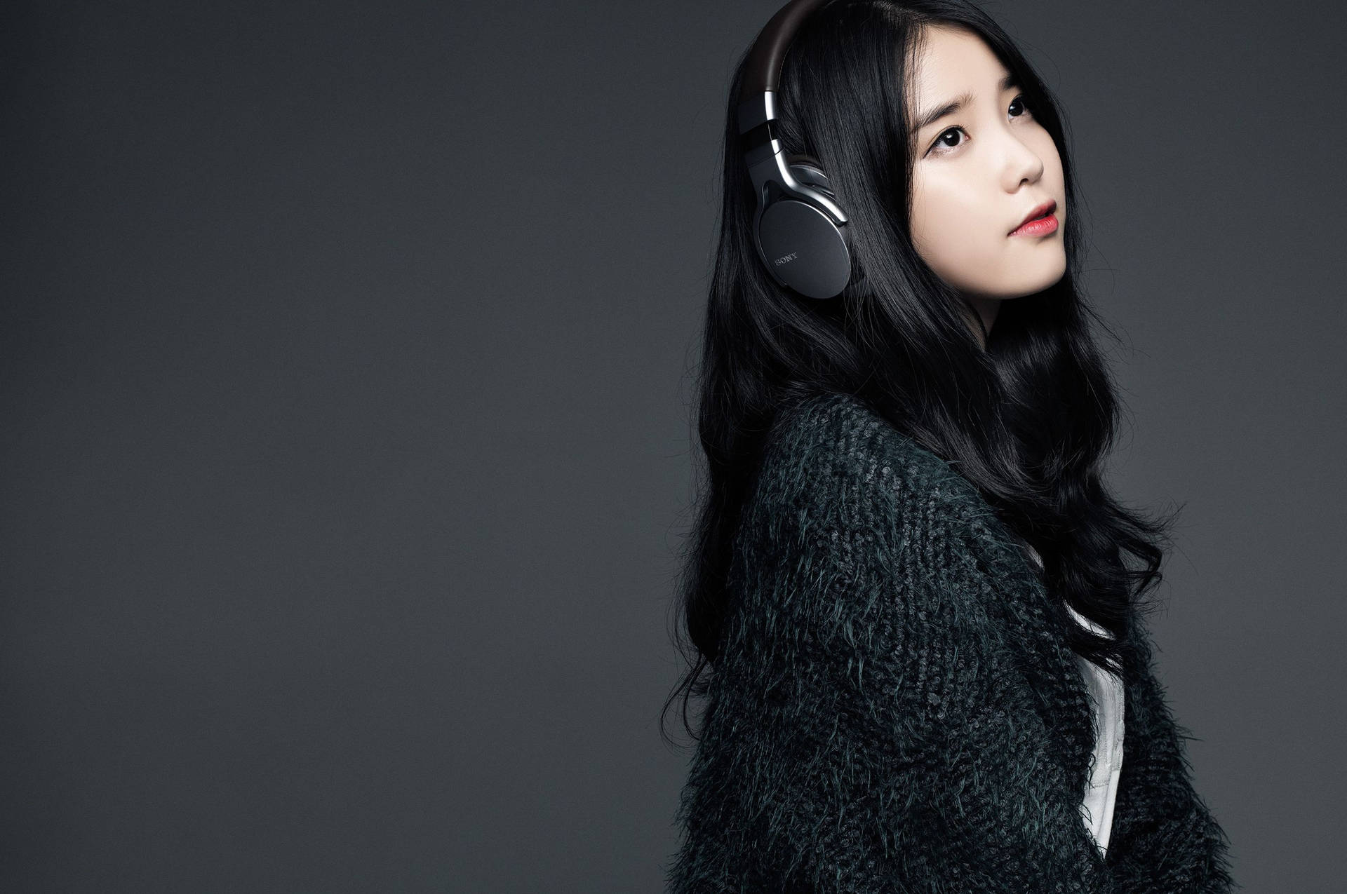 年輕女性在攝影棚中戴著耳機和深色毛衣。 — K Pop 壁紙