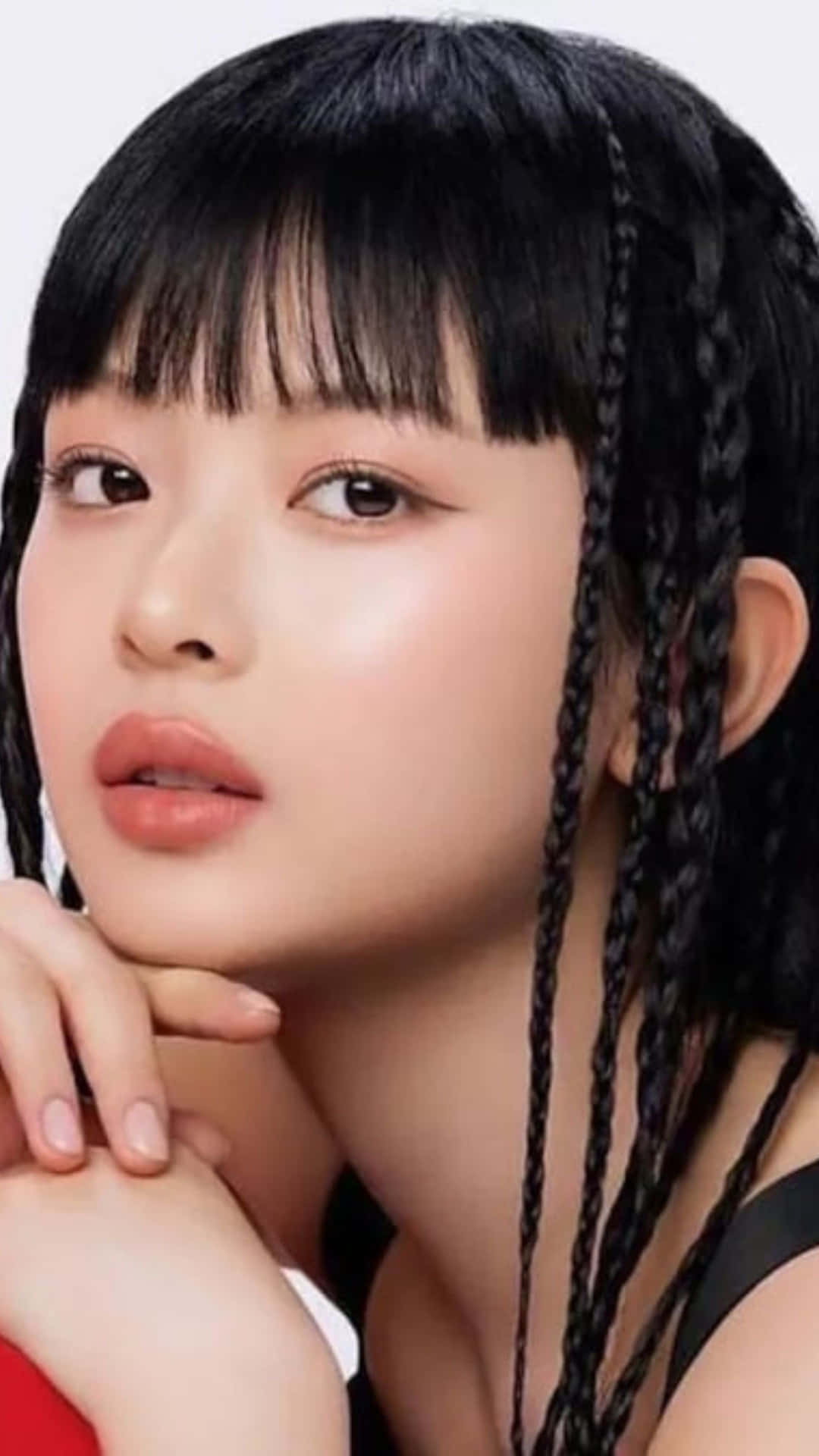  壁紙 — 一位年輕女性，黑色辮子頭髮和瀏海，輕輕地將下巴擱在手上，背景為純白色。