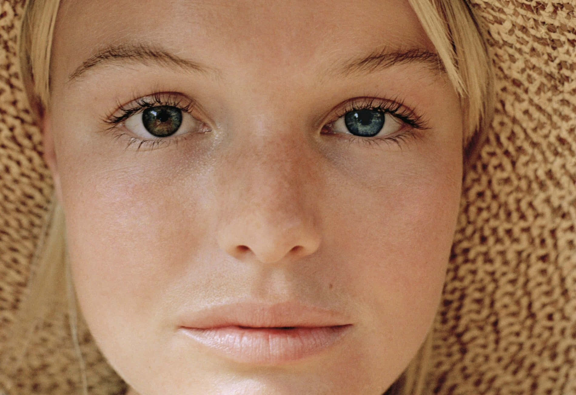 Kate Bosworth 桌布 壁紙 — 年輕女子近距離肖像，臉上有雀斑和引人注目的藍眼睛，戴著編織草帽。
