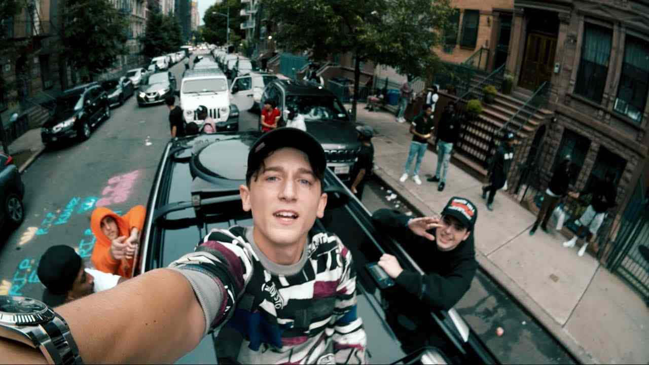  壁紙 — 一名身穿條紋襯衫和帽子的年輕男子，在繁忙的城市街道上從行駛中的汽車內與揮手的朋友們一起自拍。