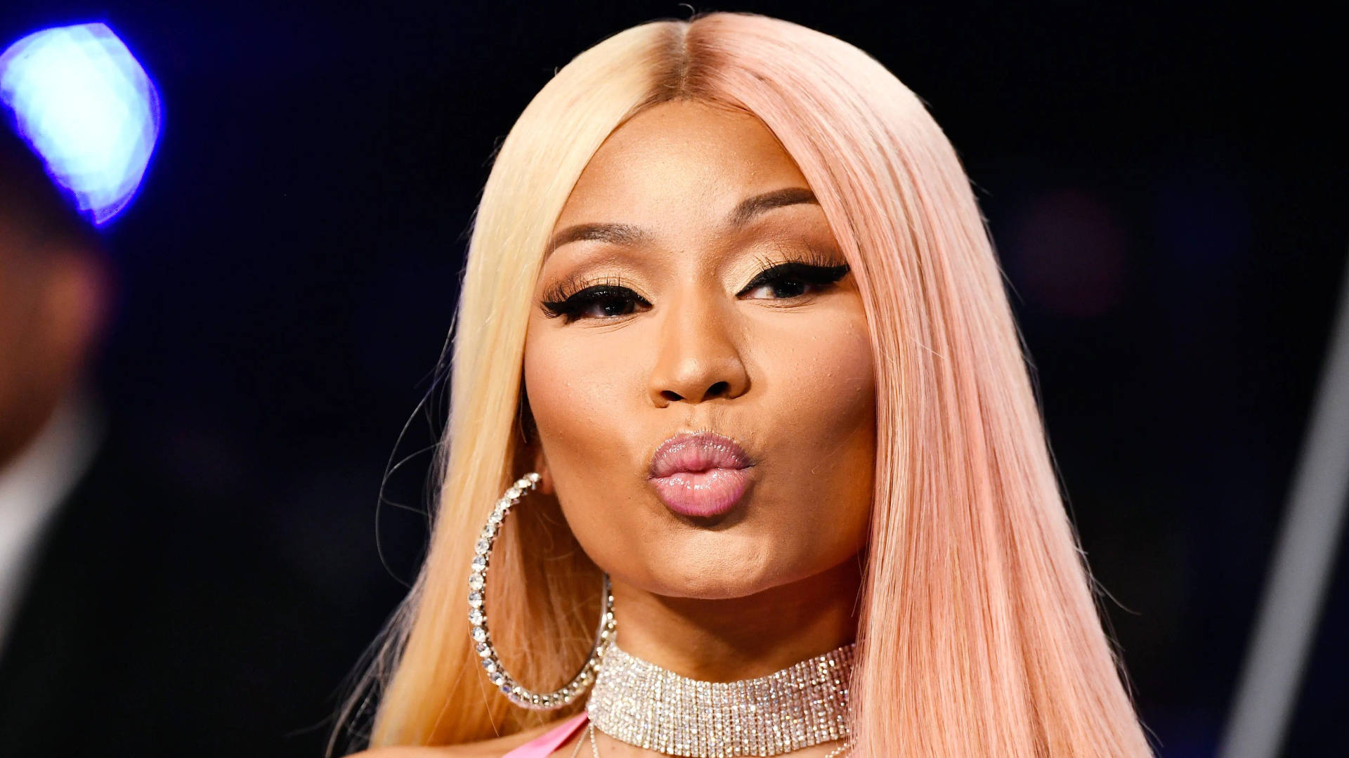 Nicki Minaj 在舞台燈光下嘟起嘴唇，戴著鑽石首飾。 — 說唱歌手 壁紙