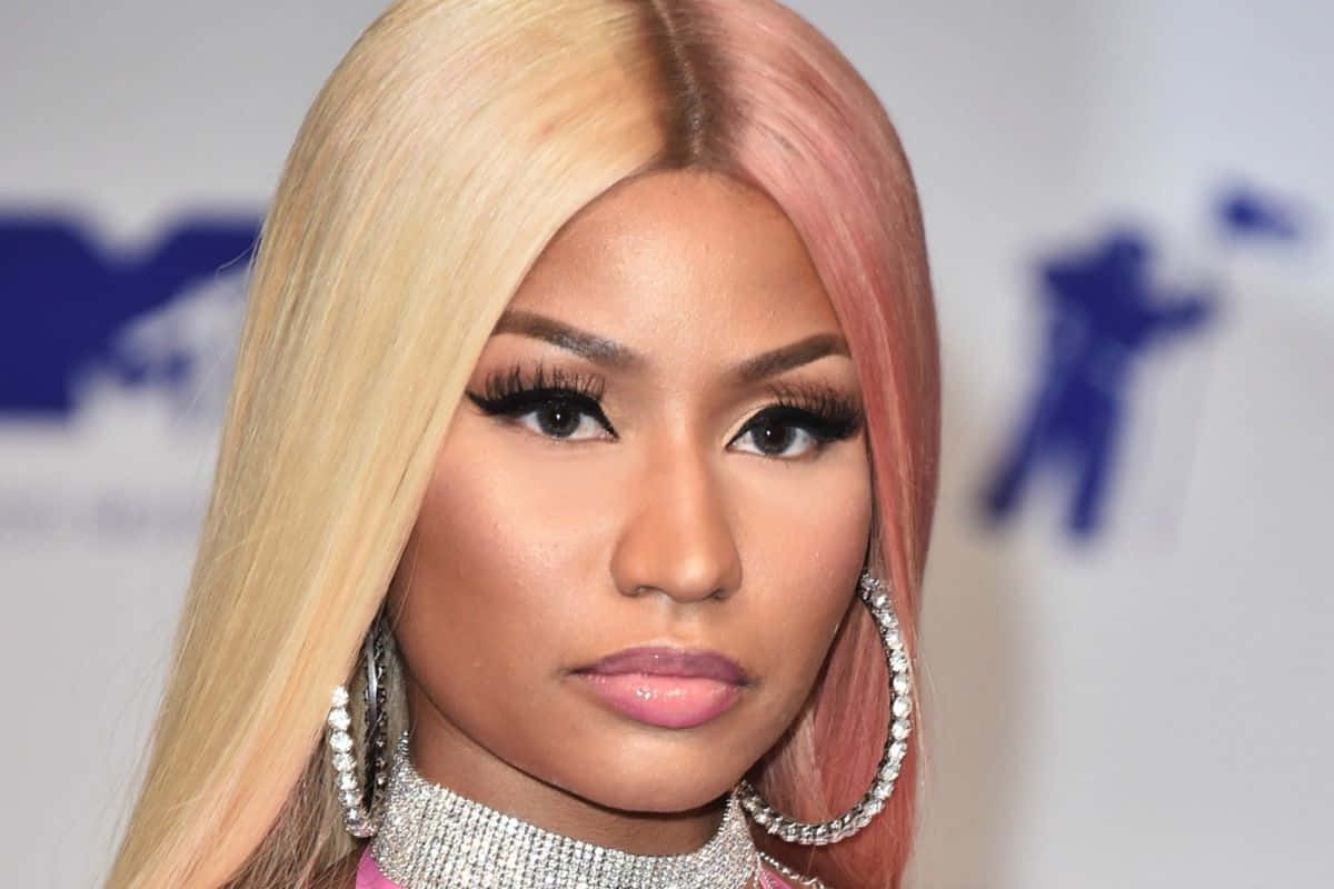 妮琪·米娜 桌布 壁紙 — Nicki Minaj 的頭像特寫，金髮和粉紅色頭髮，戴著鑽石耳環和閃閃發光的頸鏈。