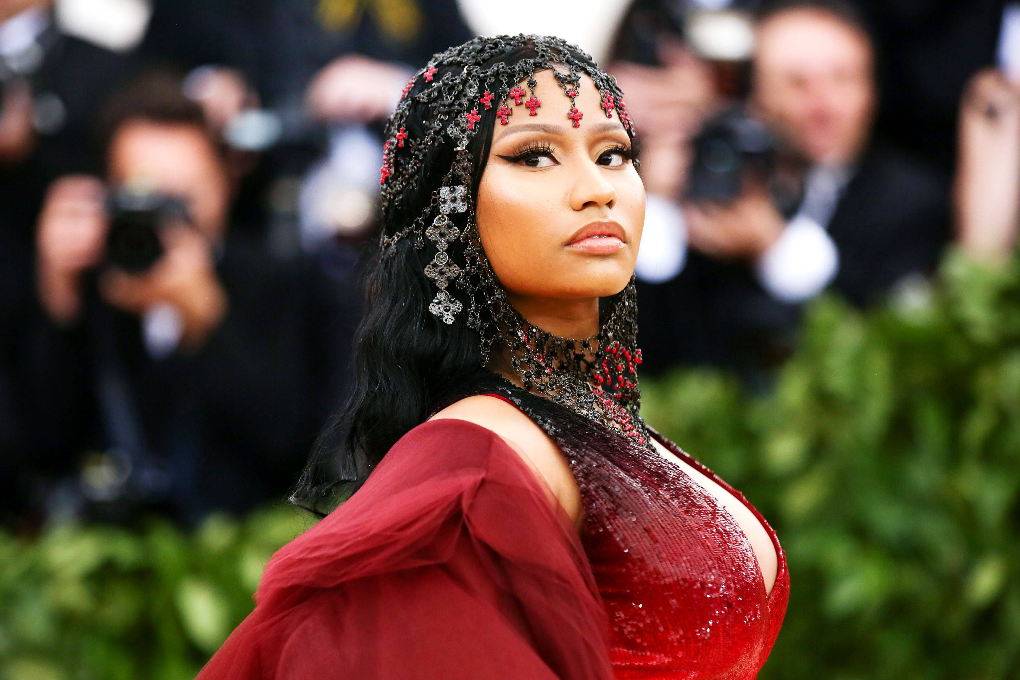 說唱歌手 桌布 壁紙 — Nicki Minaj 身穿閃耀的紅色亮片長袍和精緻的珠寶頭飾，在迷人的戶外活動中自信地擺姿勢。