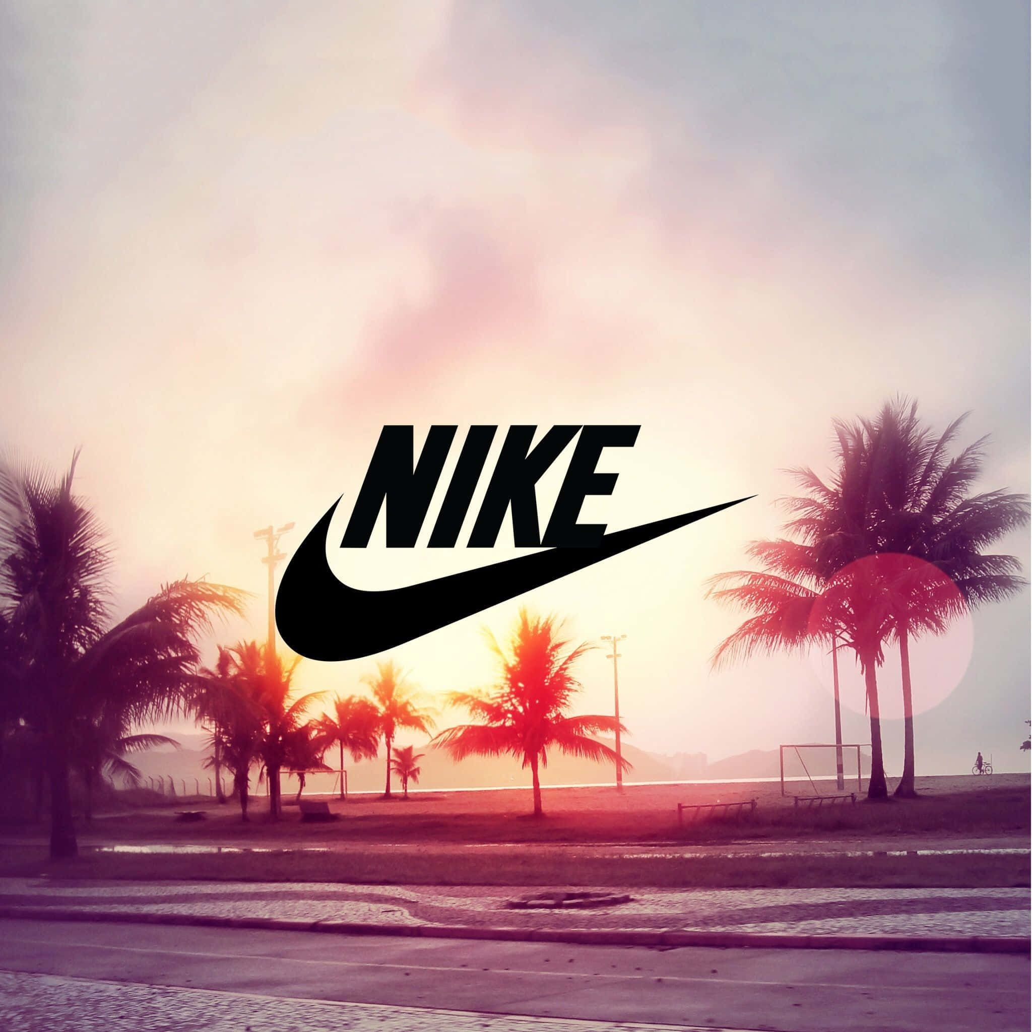 Swag 桌布 壁紙 — Nike 標誌主導了熱帶日落場景，棕櫚樹和海邊小路沐浴在溫暖的粉紅色和橙色色調中。