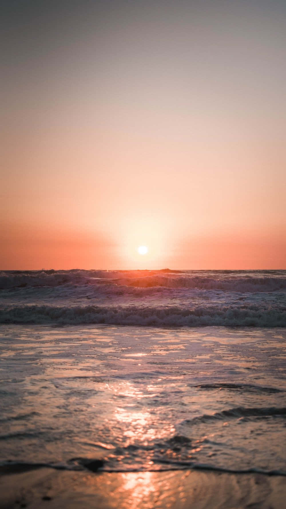 Sunset Photography 桌布 壁紙 — 寧靜的海洋日落，金色波浪拍打濕潤沙灘，天空呈現柔和的粉紅與橙色。