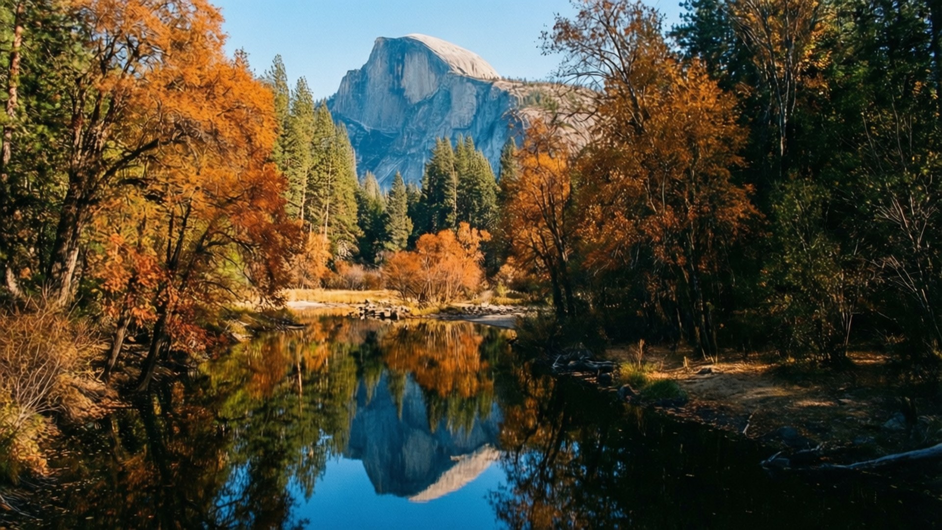 Mirror Lake Reflection 壁紙 — 寧靜的秋日河流映照著半圓頂的花崗岩面，周圍是火紅的橙色和綠色樹木，在清澈的藍天下。