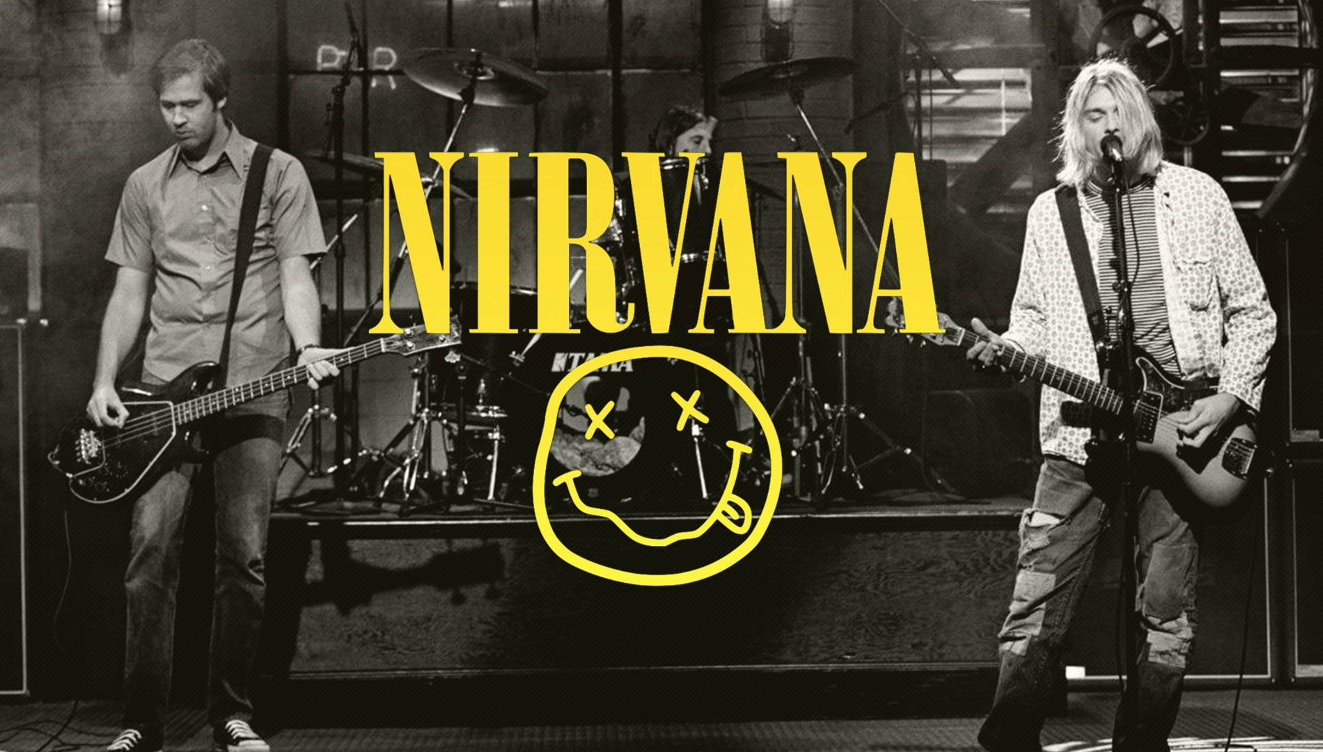 nirvana 4K 桌布 壁紙 — Nirvana 樂團在舞台上表演的黑白照片，上面疊加了標誌性的黃色笑臉標誌。