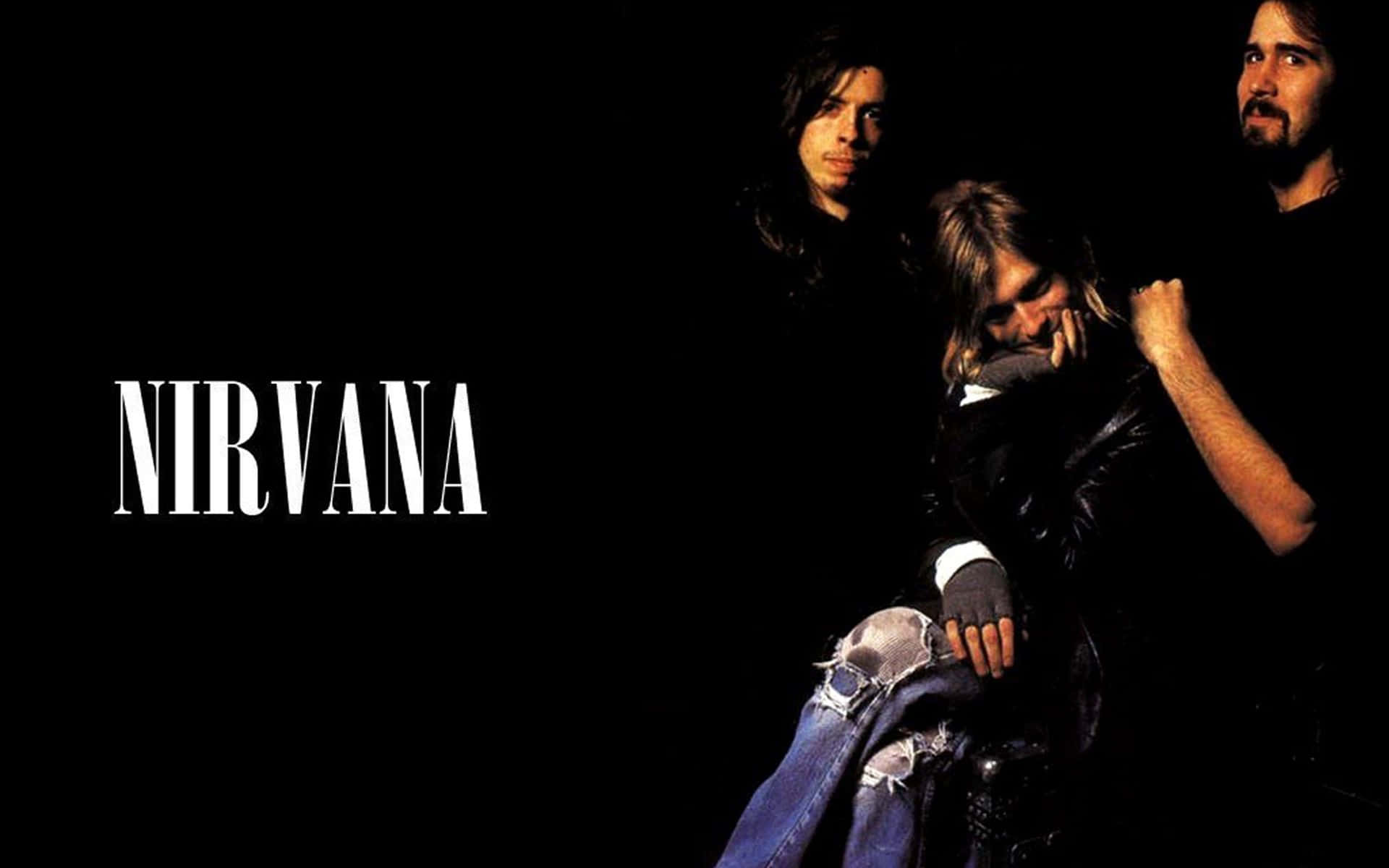 nirvana 桌布 壁紙 — Nirvana 的三位樂團成員身穿深色衣服，在黑色背景前擺姿勢，樂團名稱以粗體白色文字顯示。