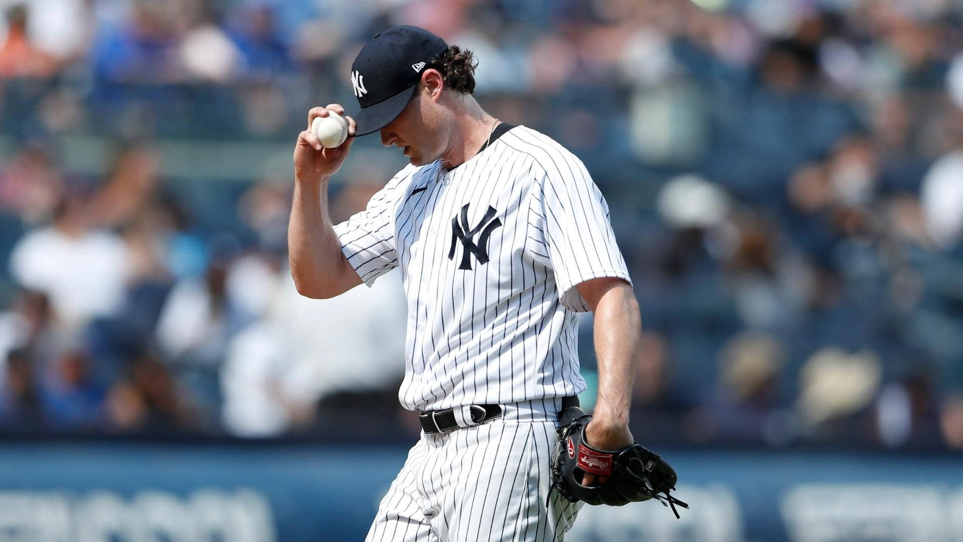 身穿洋基隊服的棒球投手在球場將球貼在額頭上。 — MLB 壁紙