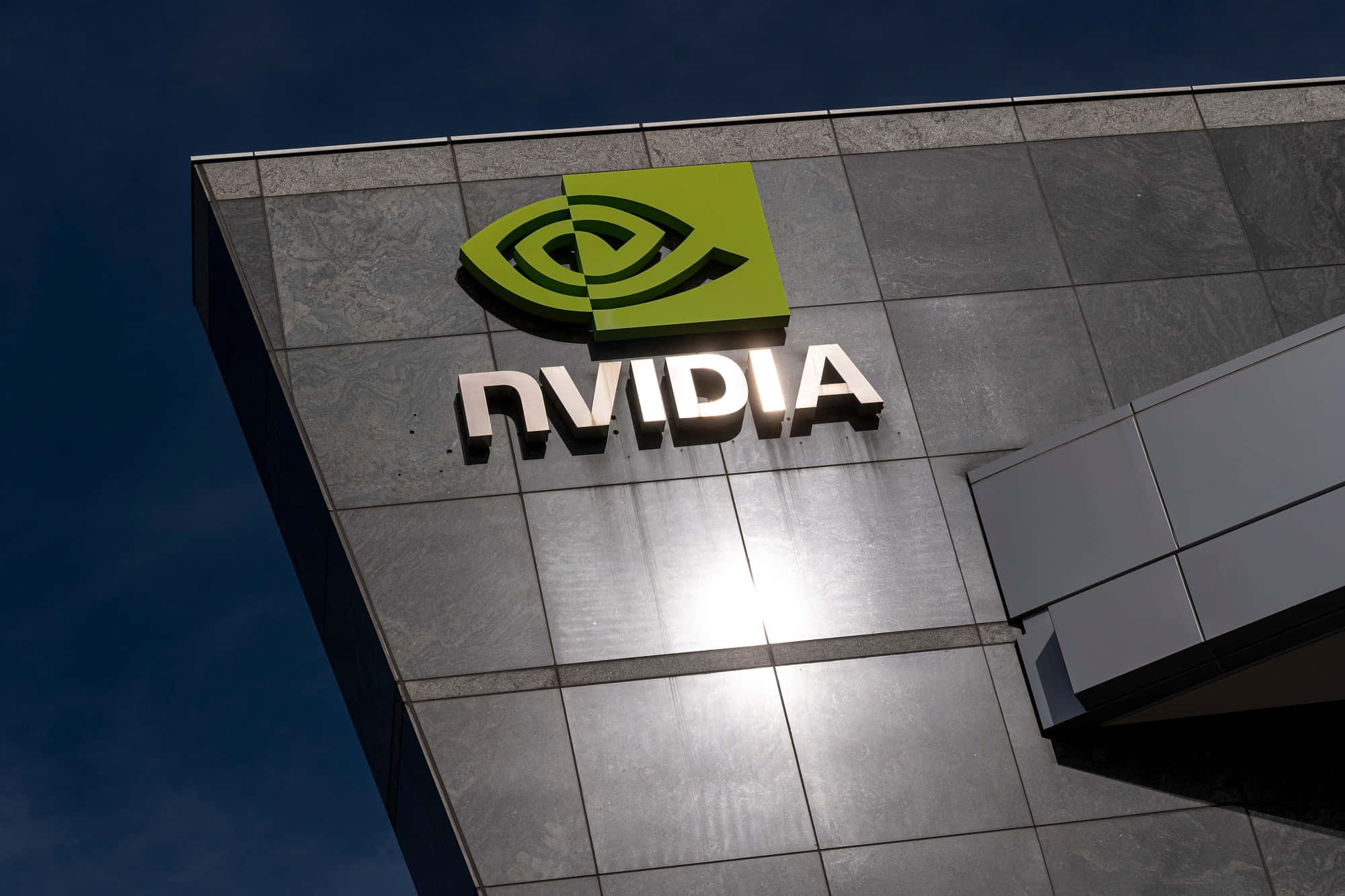 Nvidia 標誌矗立於建築物上，背景為藍天 壁紙
