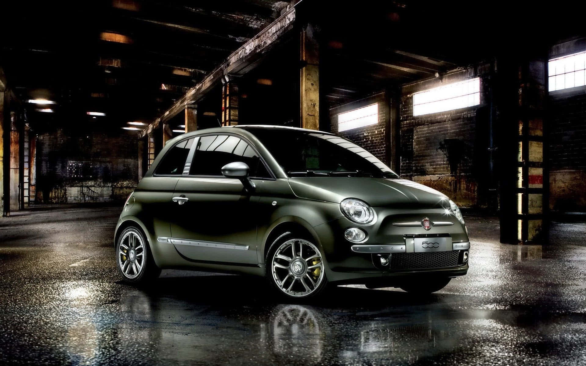 Fiat 500l 桌布 壁紙 — 一輛時尚的橄欖綠色菲亞特500停放在光線昏暗的工業倉庫中，地面潮濕反光。