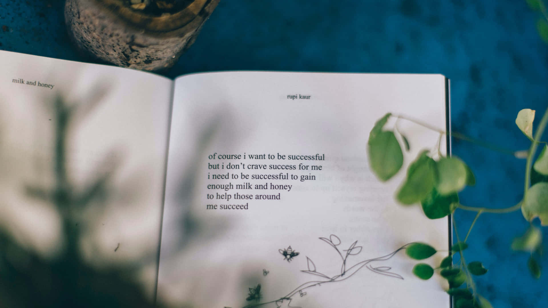 打開的書，詩歌被綠色樹葉和陶瓷花盆環繞，放在藍色表面上。 — 語錄 壁紙