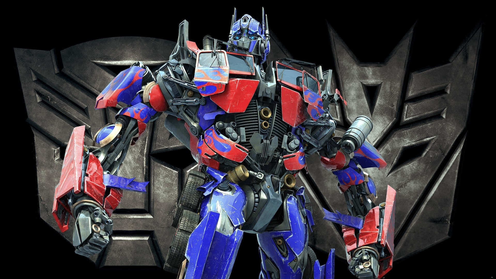  壁紙 — Optimus Prime 英雄地站在一個巨大的博派標誌前，紅、藍、銀色的裝甲在戲劇性的燈光下閃耀。