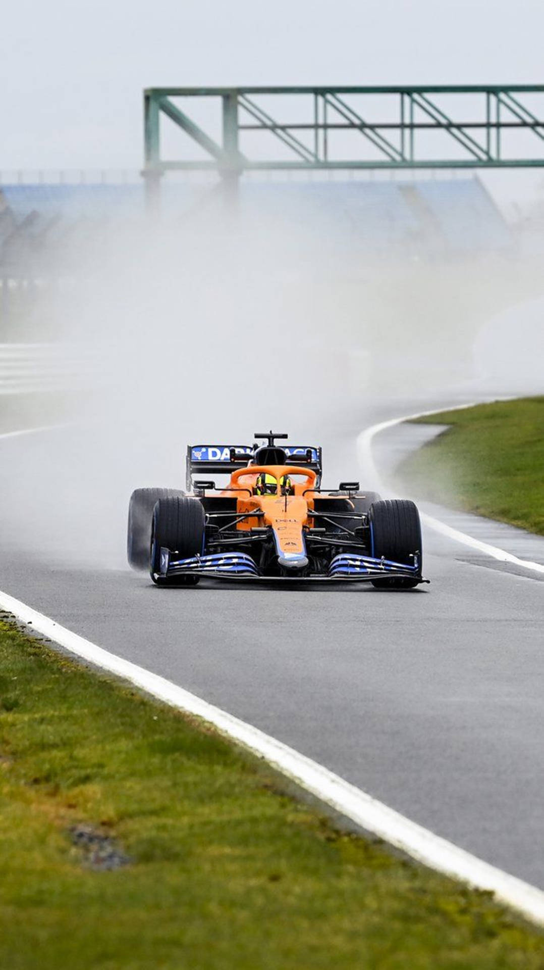 橙色和藍色賽車在潮濕賽道上高速行駛，激起水霧 — F1 壁紙