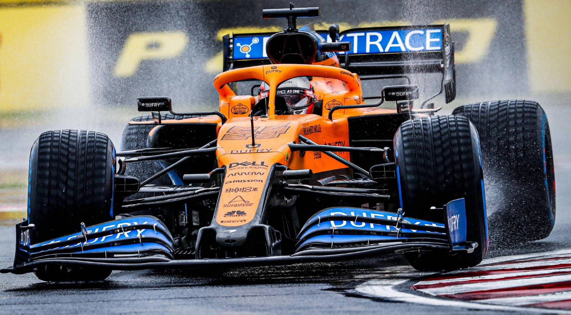 橙色和藍色的一級方程式賽車在潮濕賽道上噴水疾馳。 — F1 壁紙