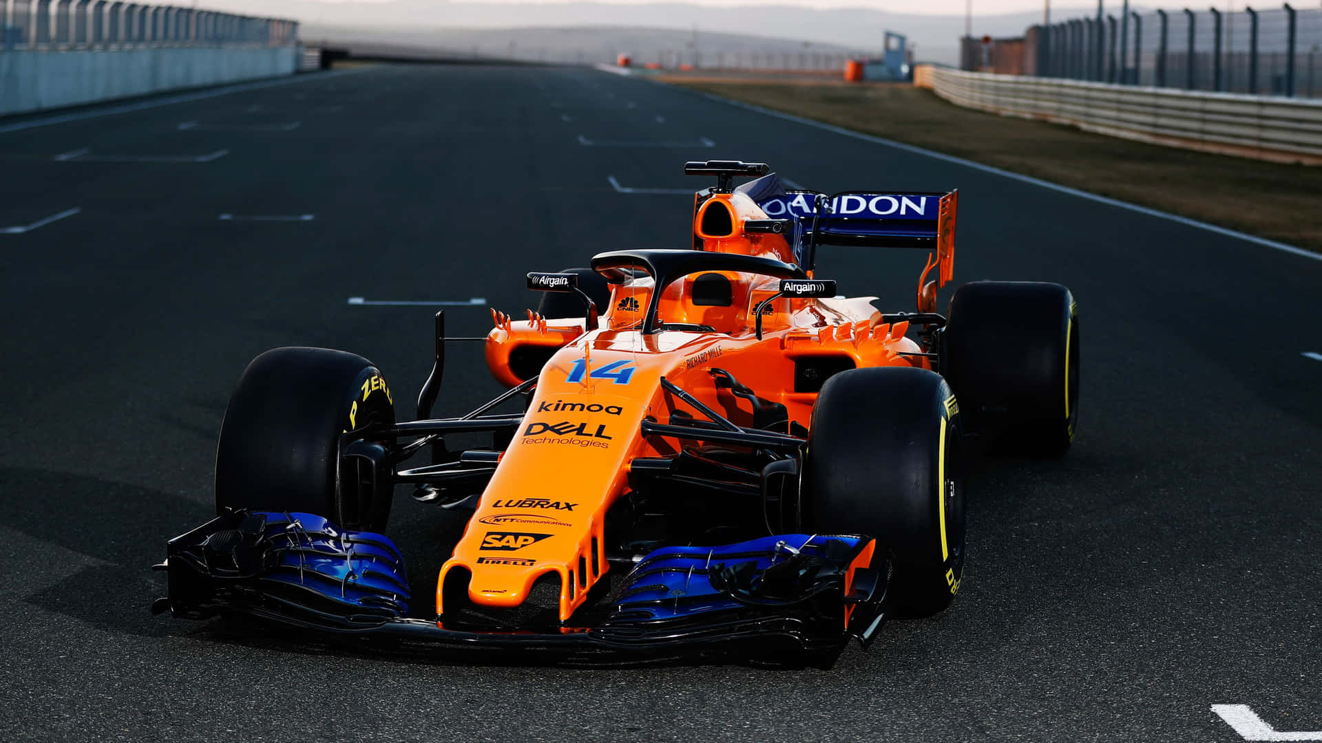 日落時分，賽道上的一輛橙色和藍色 Formula 1 賽車。 — F1 壁紙
