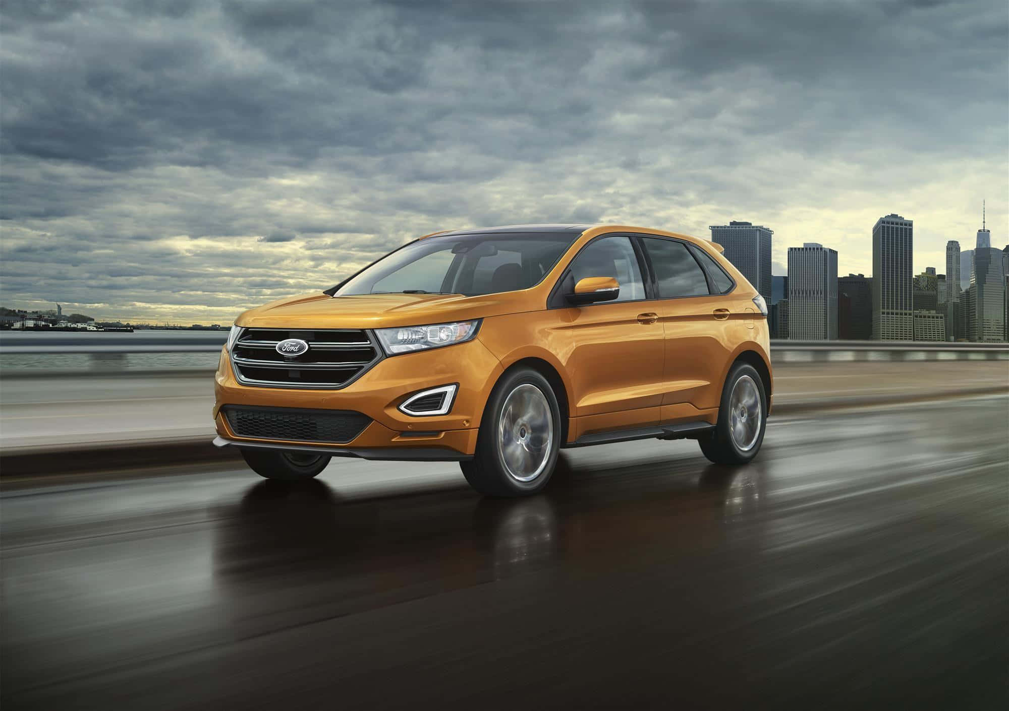 Ford Edge 桌布 壁紙 — 一輛充滿活力的橙色福特Edge SUV在濕滑的橋上疾馳，背景是陰雲密佈的城市天際線。