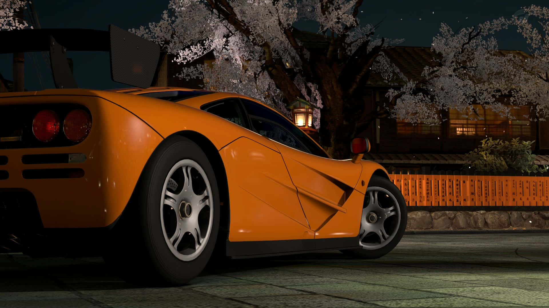 Mclaren F1 桌布 壁紙 — 一輛鮮豔的橙色McLaren F1跑車在夜間停放在發光的櫻花樹下，靠近傳統的日本燈籠。