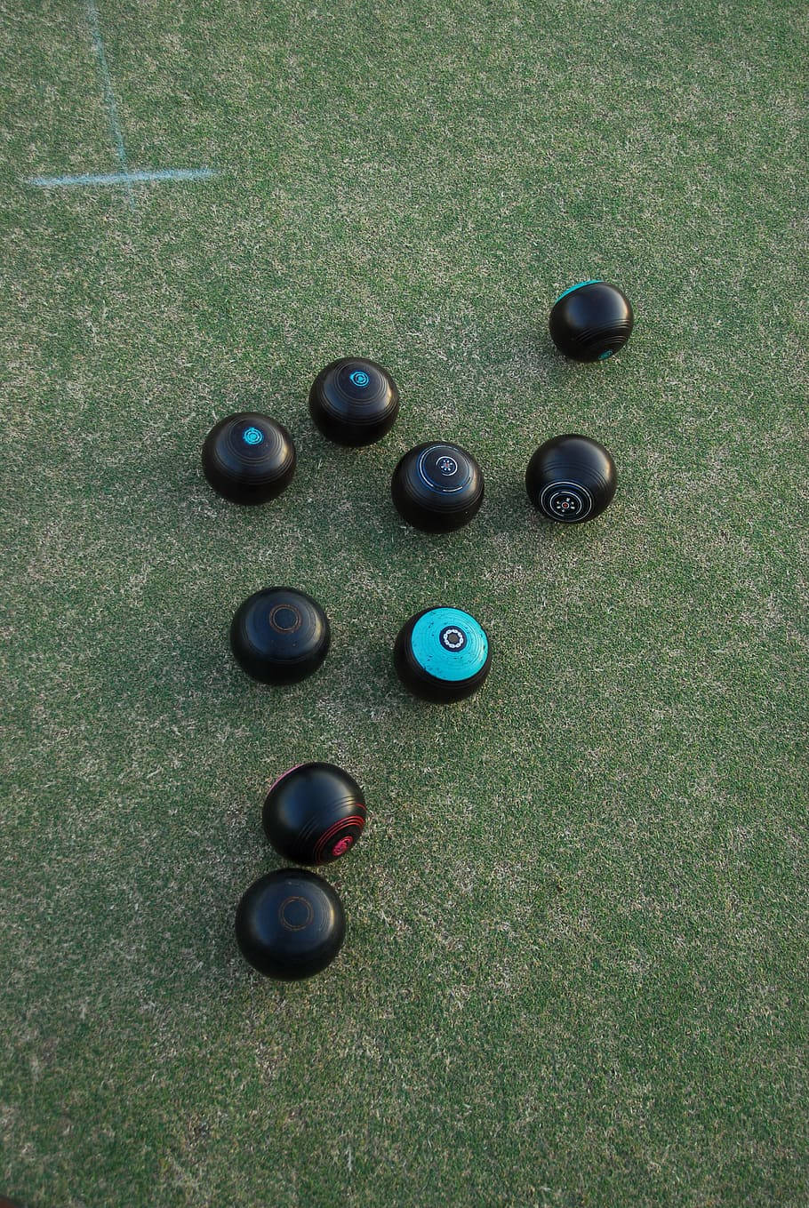 運動 桌布 壁紙 — Overhead view of black and teal lawn bowls scattered on textured green artificial turf with chalk markings.