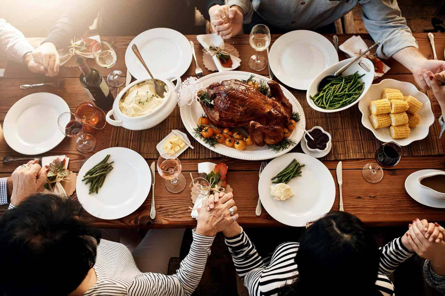 Dish 桌布 壁紙 — Overhead view of family hands clasped in prayer around a rustic wooden table laden with roasted turkey corn and green beans.