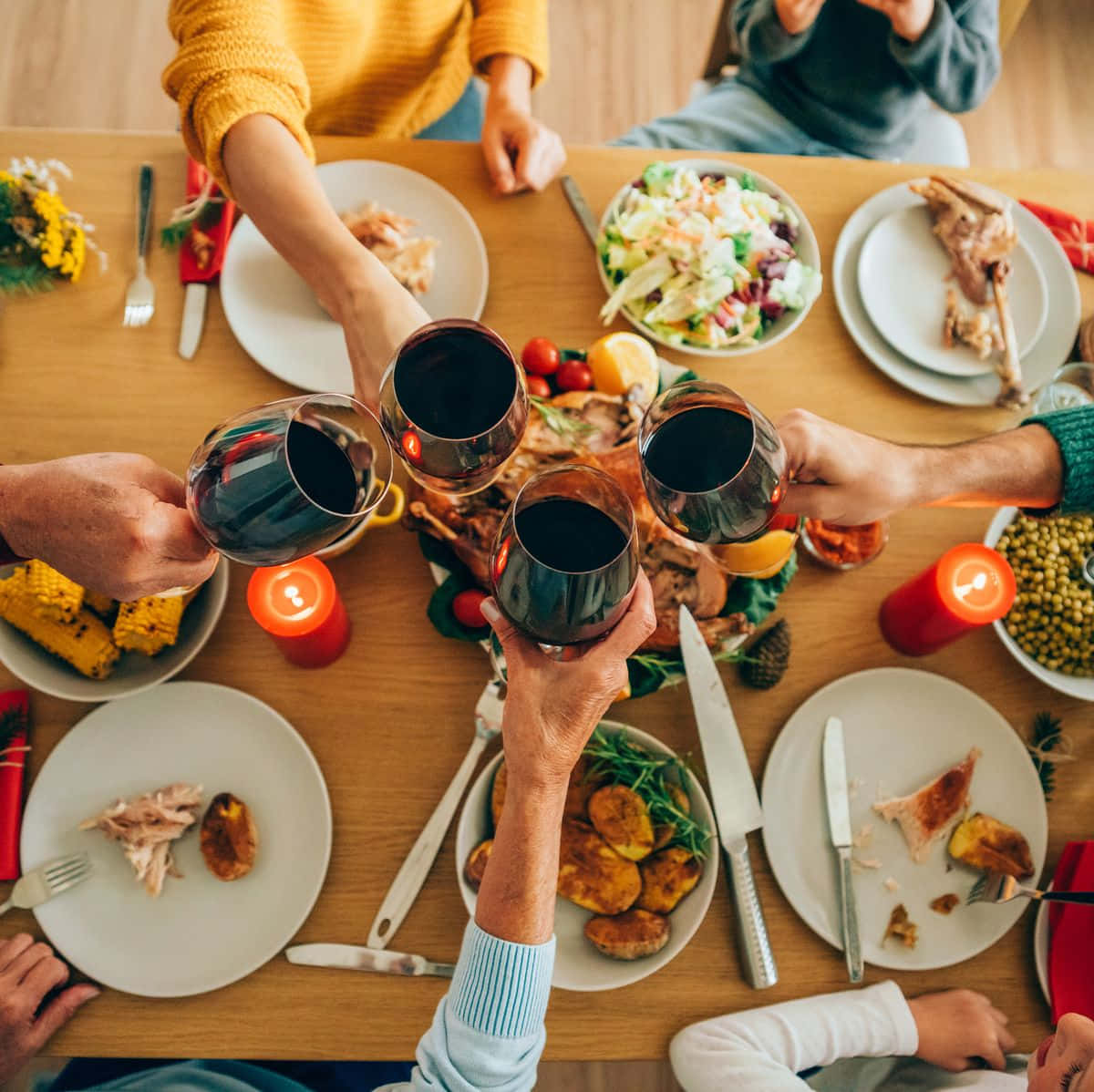 Beautiful Food 桌布 壁紙 — Overhead view of family toasting with red wine glasses around a festive dinner table filled with roasted turkey corn and candles.
