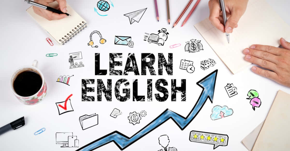 English 桌布 壁紙 — Overhead view of hands writing around bold 'LEARN ENGLISH' text with upward arrow and educational doodles on white desk.