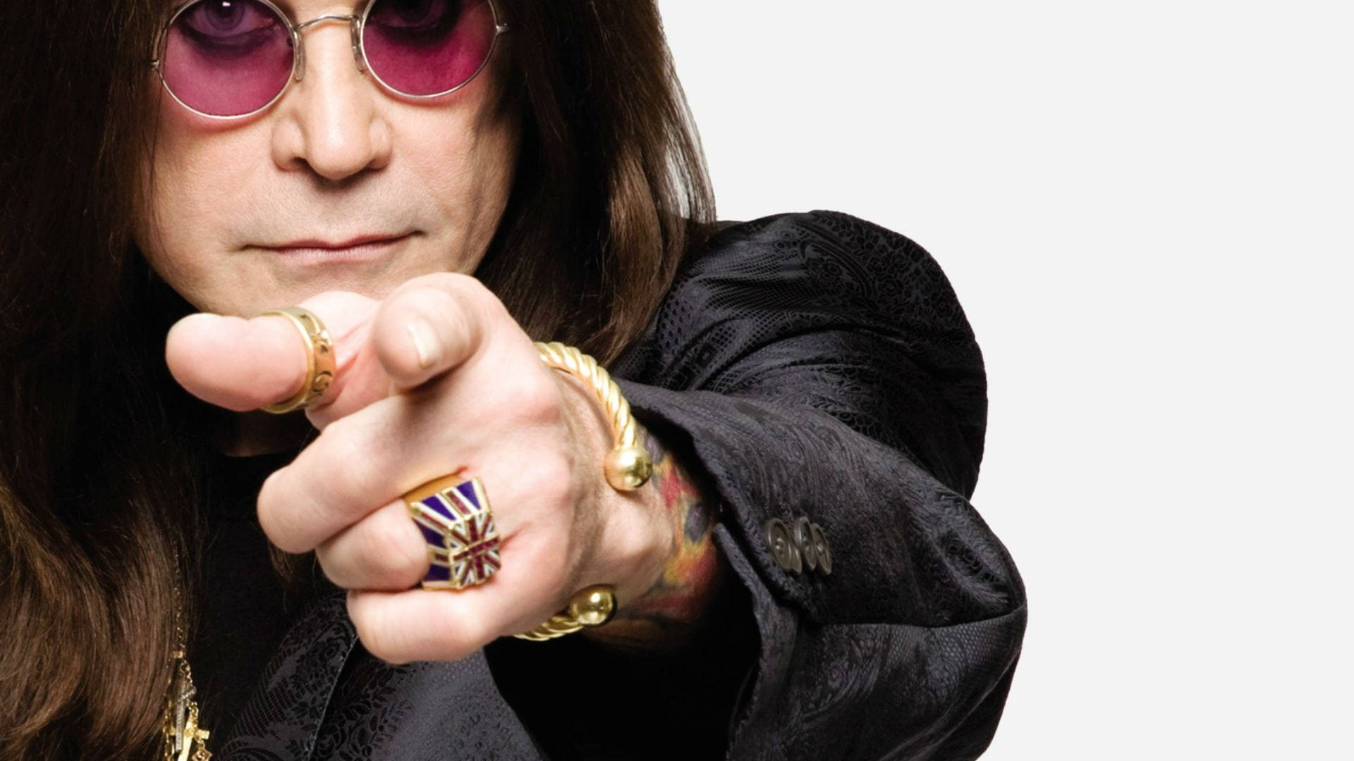 Ozzy Osbourne 桌布 壁紙 — Ozzy Osbourne 戴著粉紅色太陽眼鏡和金色戒指，在純色背景下以強烈的目光直視觀眾。