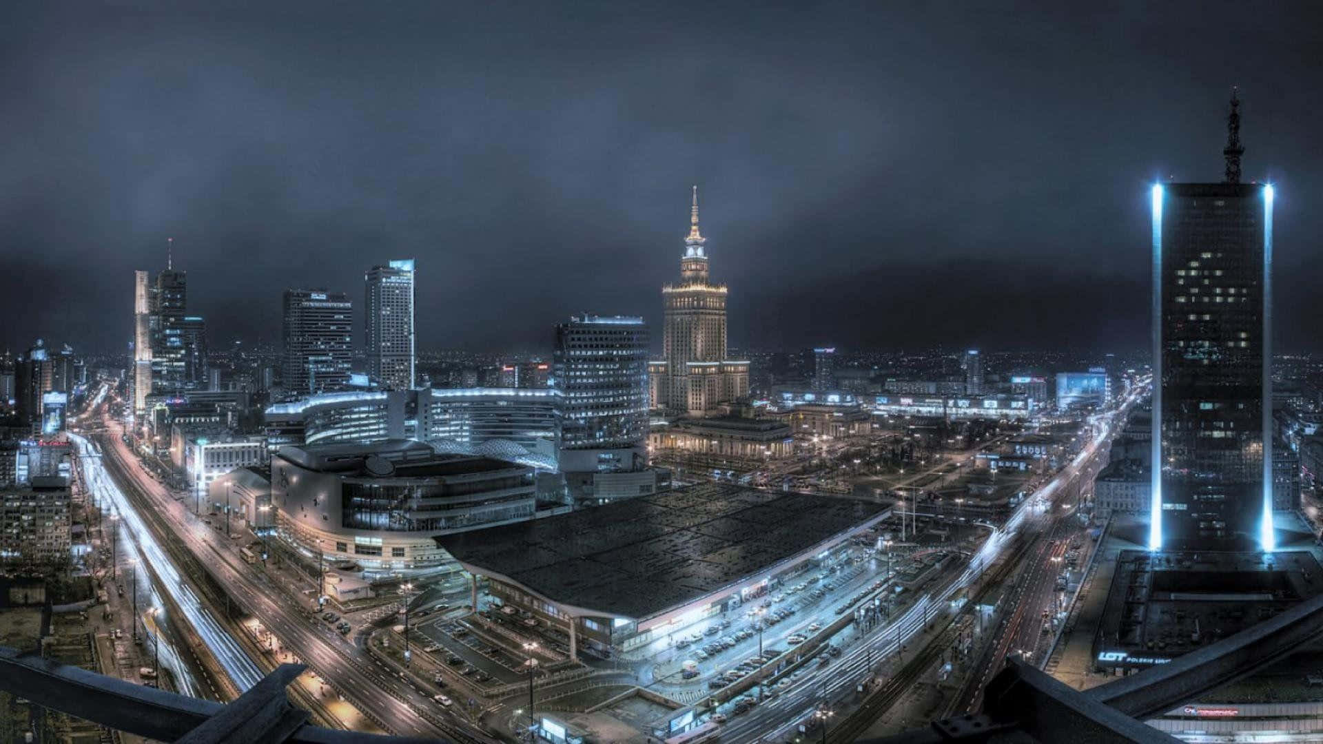  壁紙 — 現代城市景觀的夜間全景，有燈火通明的摩天大樓和發光的街燈。