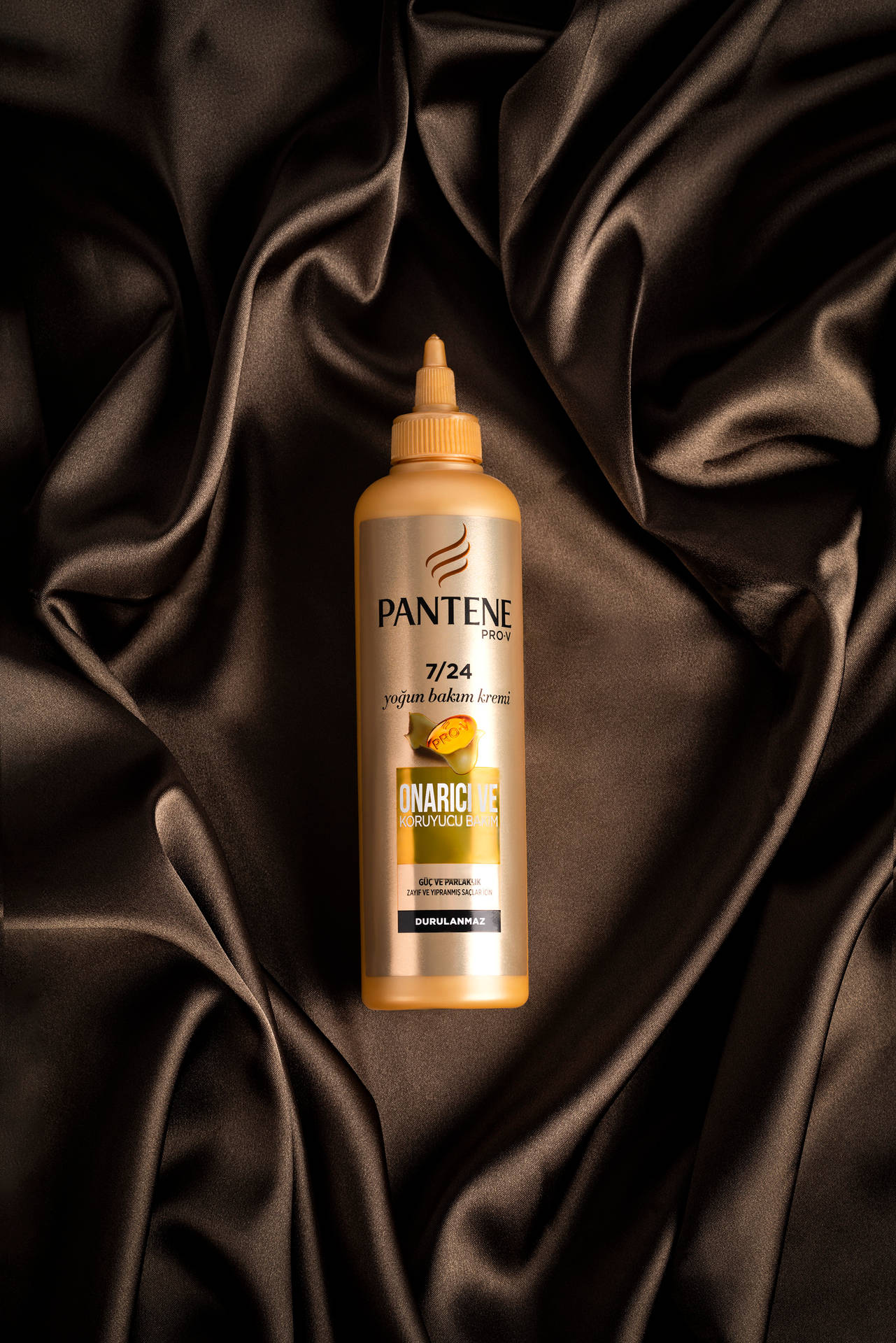 深色緞面布料上的 Pantene 護髮精華瓶 — iPad 壁紙