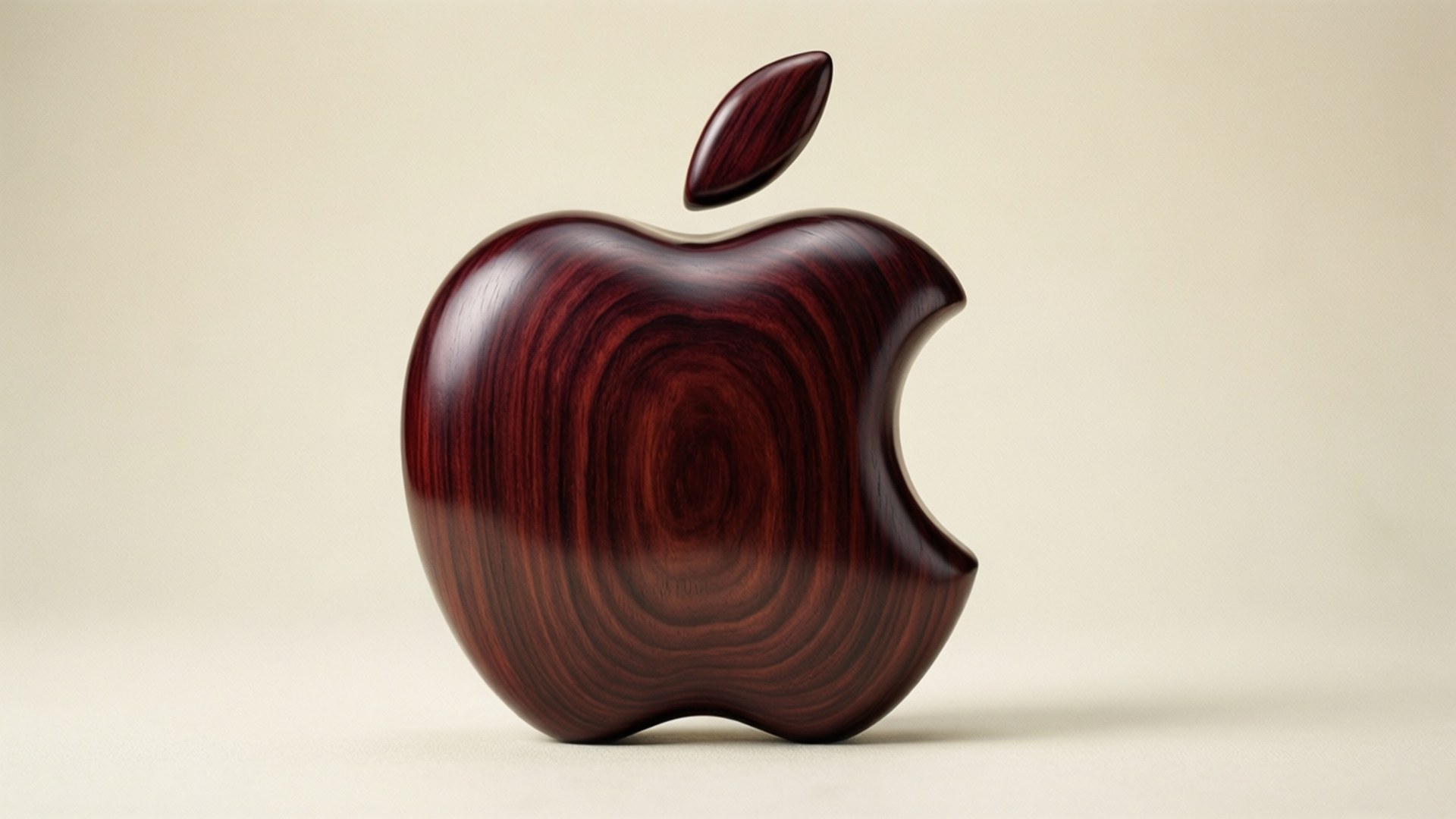 Wooden Apple Logo 壁紙 — 一個拋光的深色木蘋果雕塑，帶有咬痕和葉子，背景為米色。